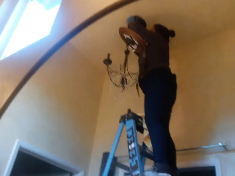 Electrician installing a chandelier in a Upper Freehold residence
